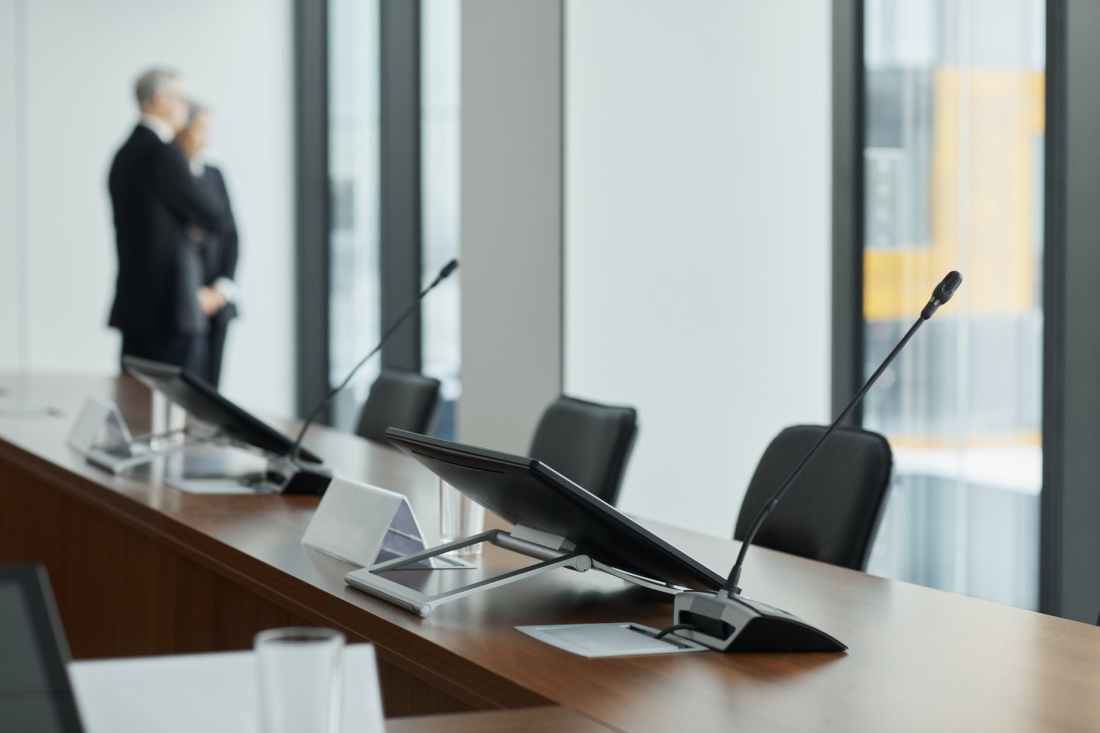 monitors and microphone on a wooden conference table